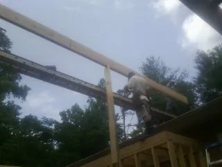 Carpenter setting a ridge beam over a new addition frame — Ice Dam Removal by Roofing Brothers in Holderness