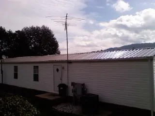New metal roof on a single wide mobile home with a TV antenna in Holderness