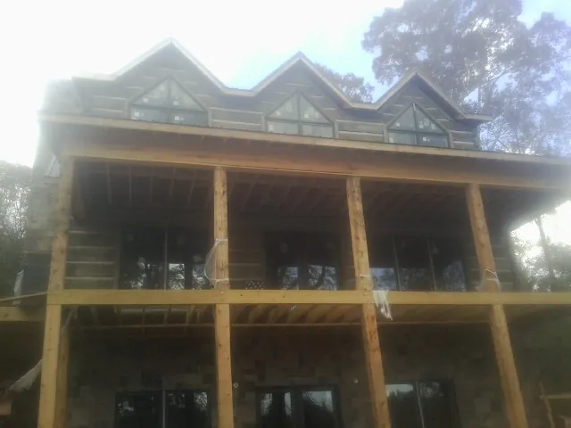 Dormers and porch framing on a large log home under construction — Roof Coating work by our crew in Holderness