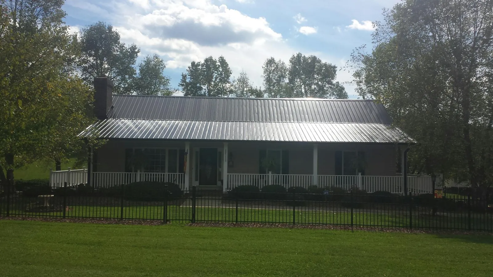 Gray metal roof on a brick ranch with a full width front porch — Gutter Guard Installation work by our crew in Holderness