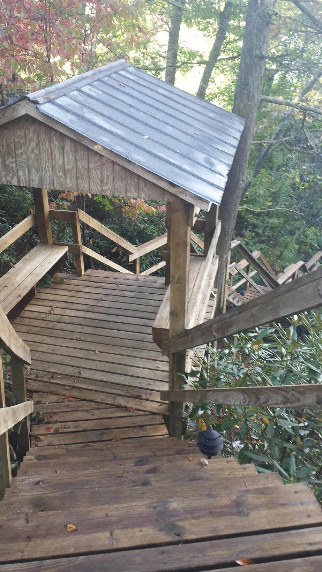 Metal roofed shelter over wooden steps on a wooded walkway — Skylight Repair & Installation work by our crew in Holderness