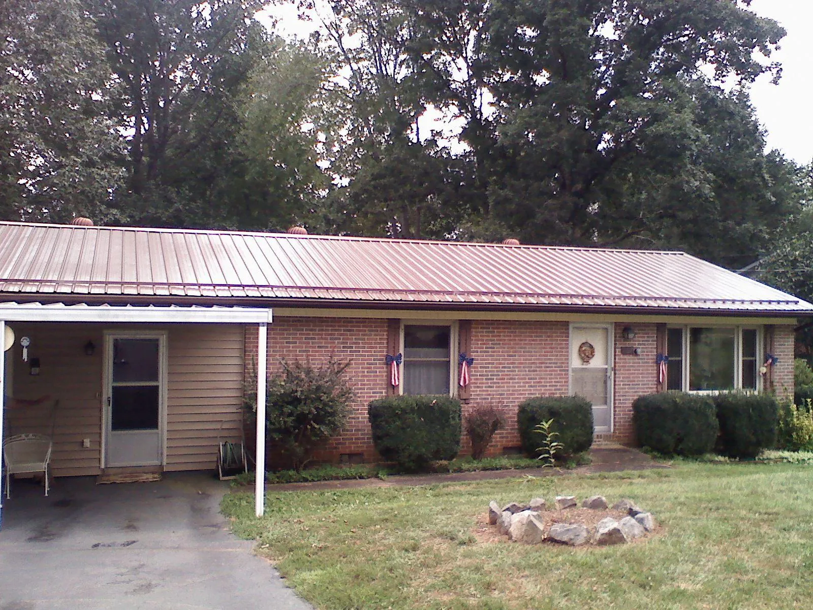 Bronze metal roof and carport on a brick ranch home — Roof Repair work by our crew in Holderness