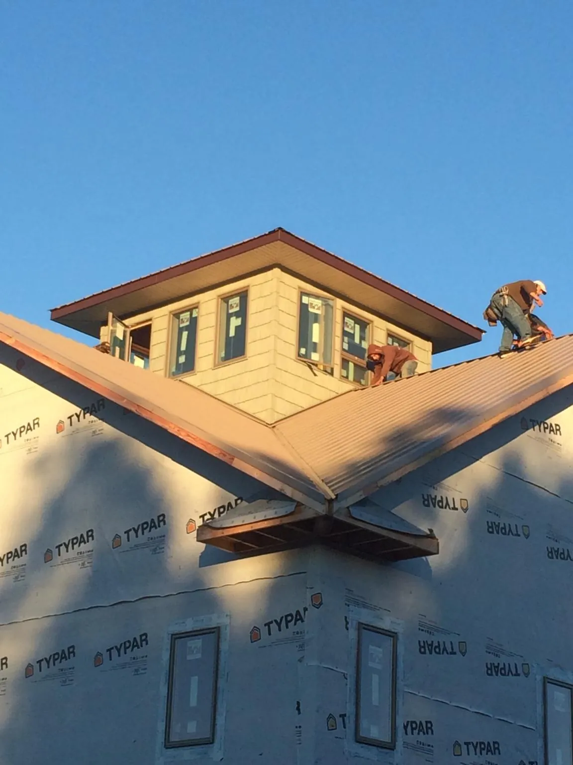 Roofers working around a rooftop cupola on a new metal roof at sunset — Roof Waterproofing in Holderness by Roofing Brothers